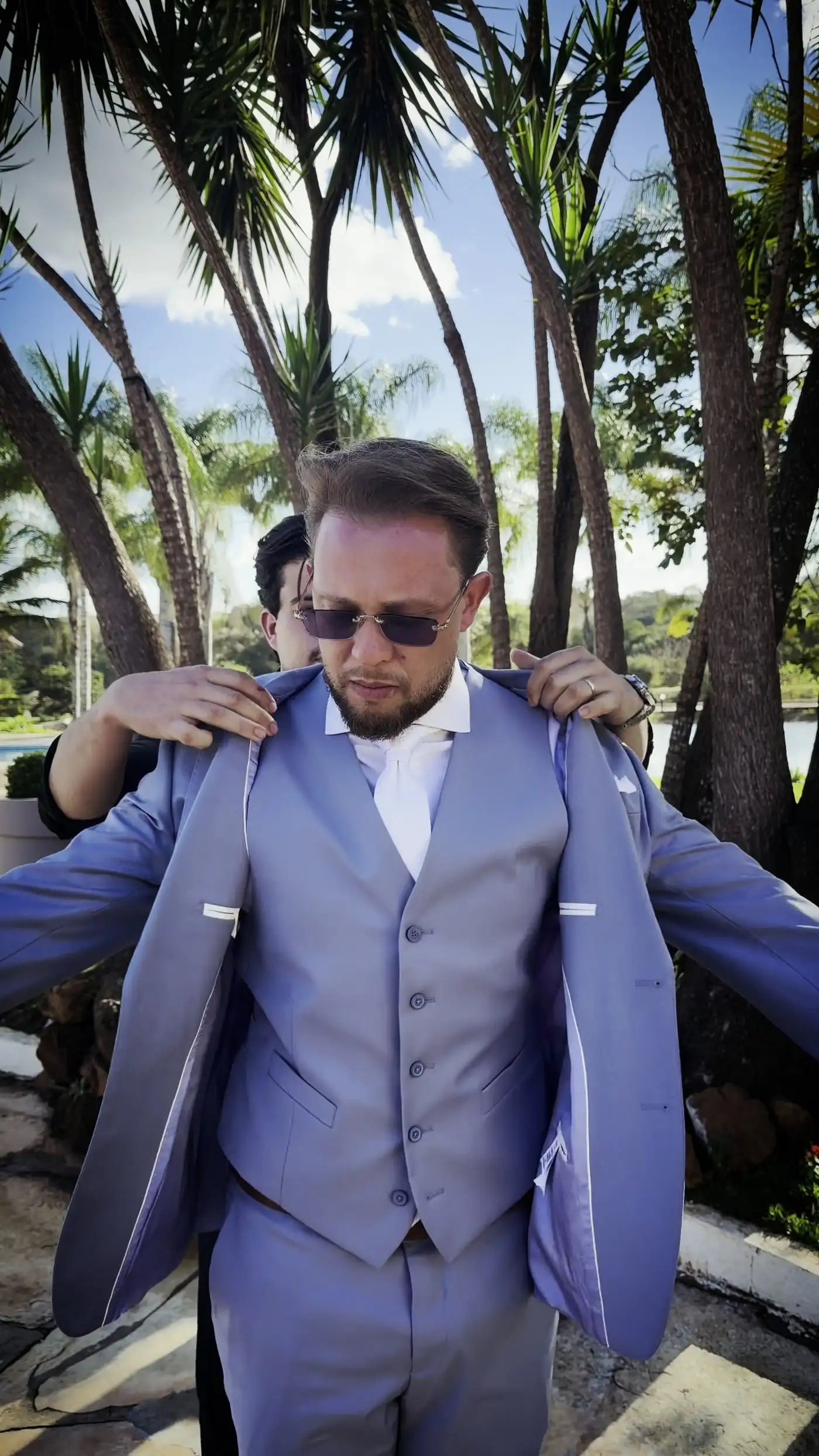 Noivo de terno sendo preparado no dia do casamento
